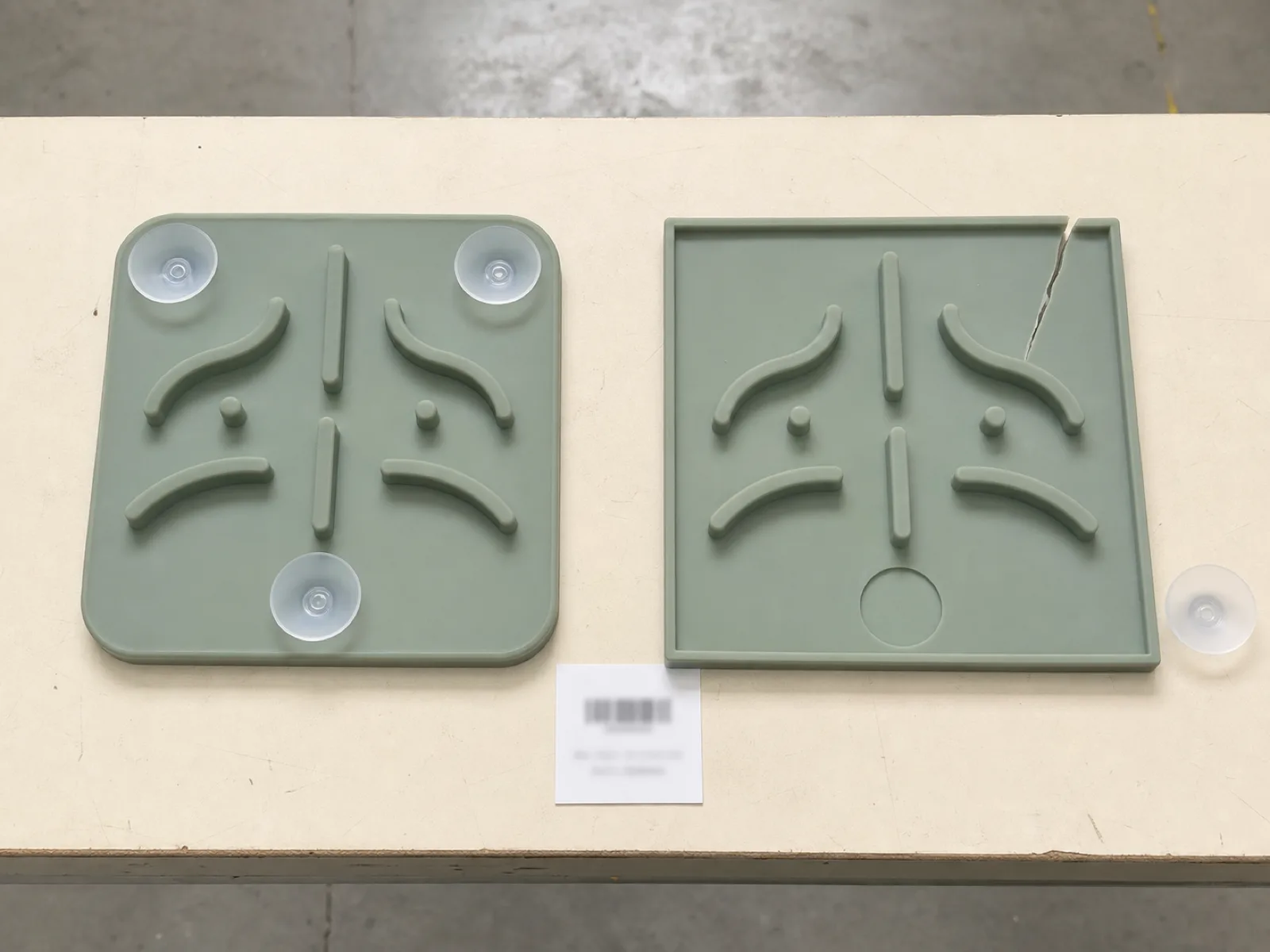 Two silicone slow feeder samples on a QC bench — one with rounded 3 mm radius corners and bonded suction cups intact, one with sharp corners showing a tear-initiation split at the edge — demonstrating pet-safe silicone product design against chew-tear failure.