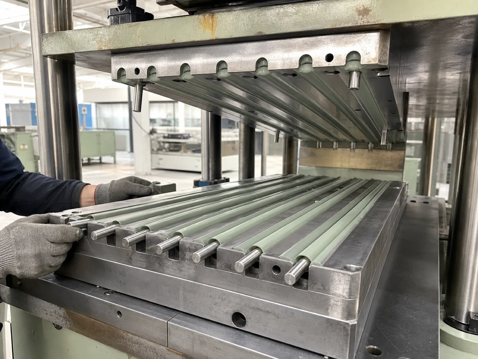 Wetop Silicone compression molding press producing a coated stainless roll-up rack with mold-bonded silicone jacket on stainless rod stock — the manufacturing method that produces the premium retail construction