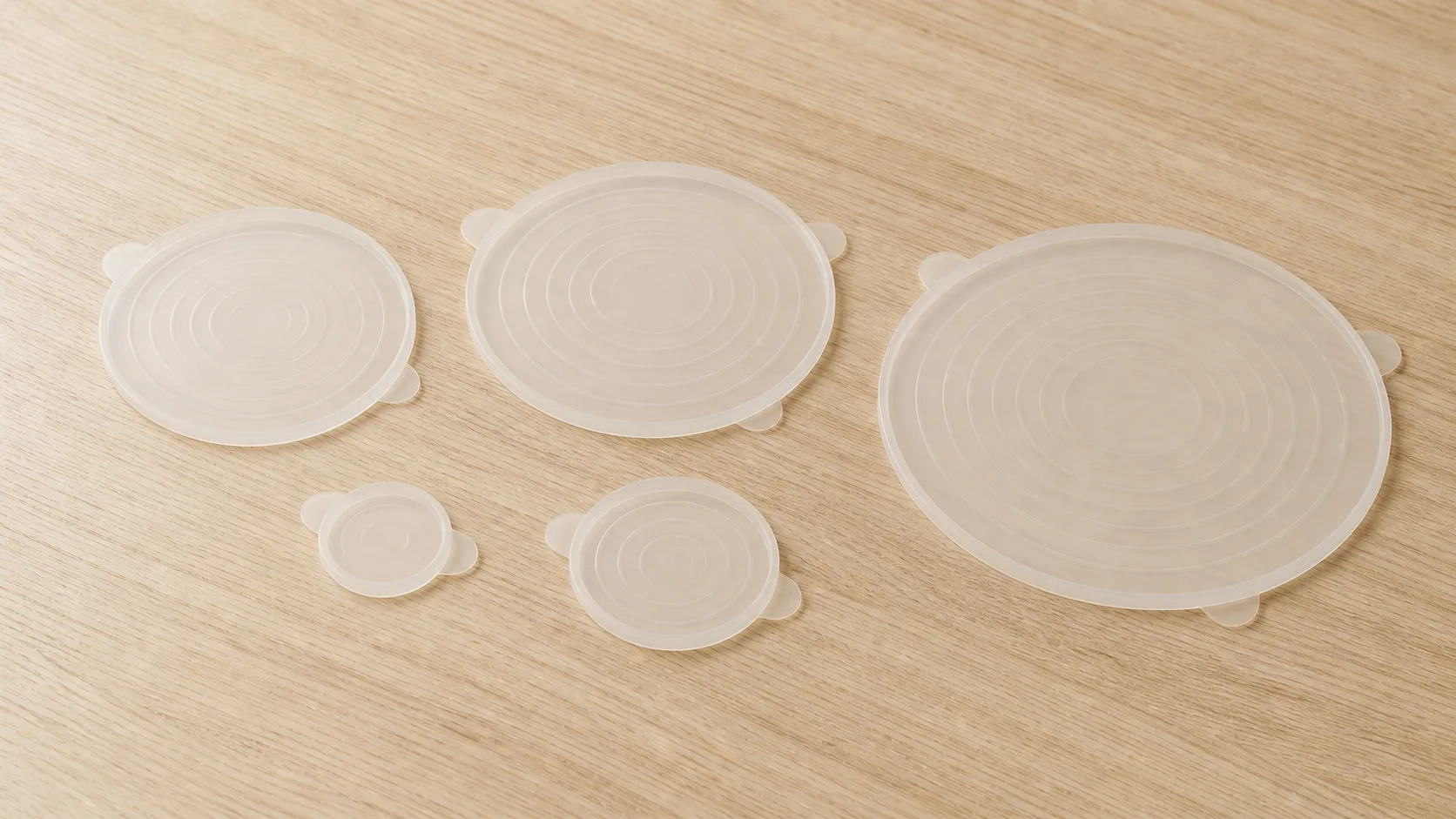 Set of translucent silicone stretch lids on a Wetop QC bench with a Shore A durometer and elongation gauge under D65 inspection light in Dongguan