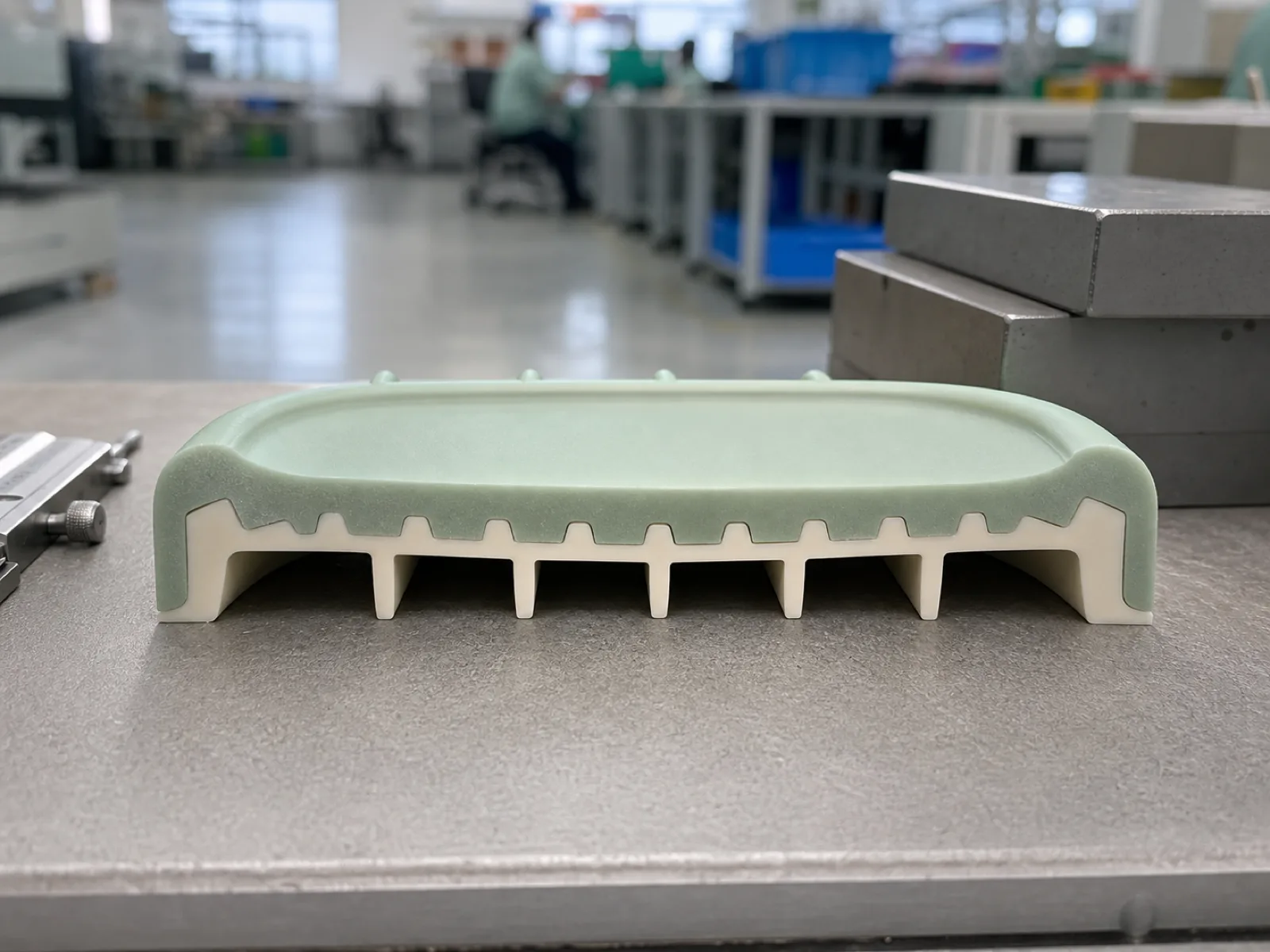 Cross-section reference of a two-durometer silicone soap dish showing 4.5 mm rib pitch drainage architecture, 2 mm rib height with 2-3 degree draft angle, and the mechanical undercut bond line between the soft top surface and rigid drainage base on a Wetop QC bench in Dongguan