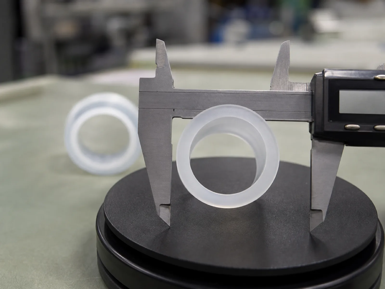 Cross-section of platinum-cured silicone tubing showing concentric ID and OD walls on a QC inspection stage with digital calipers at a silicone tubing manufacturer