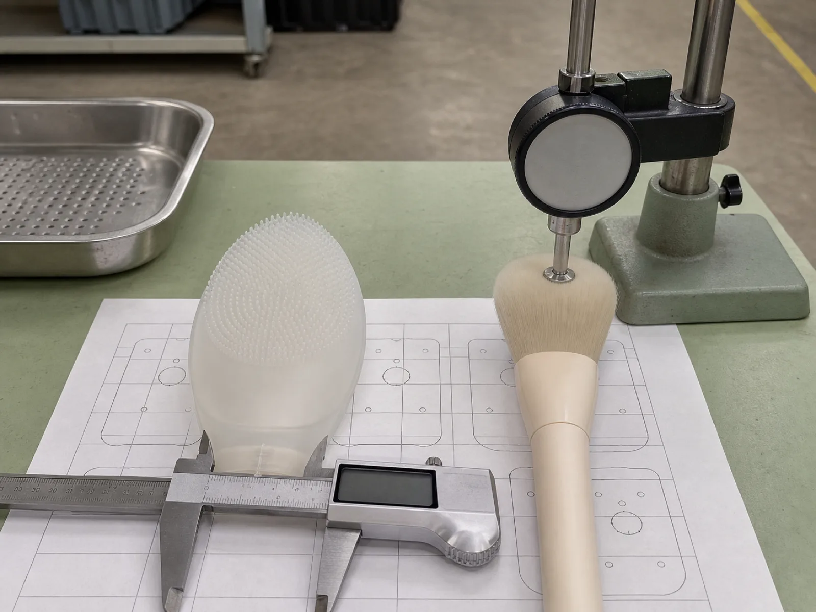Silicone makeup brush vs synthetic brush side by side on a Wetop QC bench — a translucent platinum-cured silicone nub applicator next to a cream synthetic-fiber brush, both measured with a Shore A durometer and digital caliper against a cavity-map card.